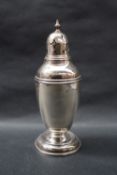 A George V silver sugar caster with a vase finial and domed cover with a tapering beaded body on a