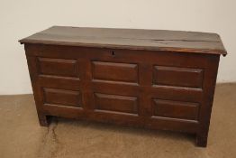 An 18th century oak coffer with a planked rectangular top above a six panelled front on stiles,