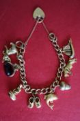A 9ct gold charm bracelet with a padlock clasp, and numerous charms, including a ship, bull, acorn,