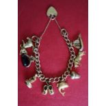 A 9ct gold charm bracelet with a padlock clasp, and numerous charms, including a ship, bull, acorn,