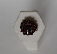 A garnet cluster ring set with three tiers of garnets to a yellow metal setting and shank,