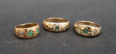 An 18ct yellow gold gypsy ring, set with two round faceted emeralds, size F 1/2,