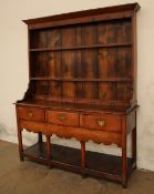 An 18th century oak South Wales dresser with a moulded cornice above two shelves,