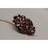 A yellow metal brooch of oval form set with rose cut diamonds, emeralds, rubies and sapphires,