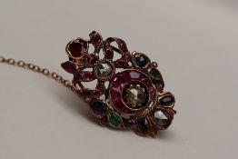 A yellow metal brooch of oval form set with rose cut diamonds, emeralds, rubies and sapphires,