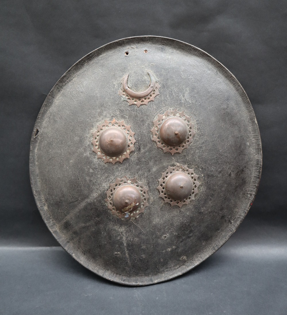 A leather shield of circular domed form with an applied copper crescent and four copper domes,