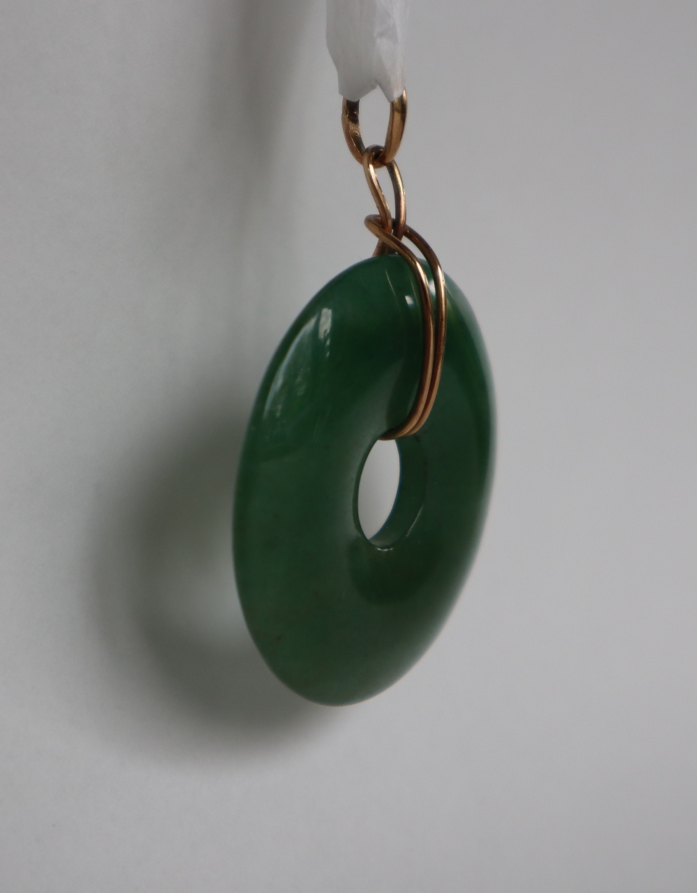 A green jade pendant of circular ring form, 4cm diameter on a yellow metal mount, - Image 2 of 3