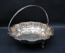 A George V silver swing handled cake basket, of lobed form on three scrolling feet, Sheffield, 1930,