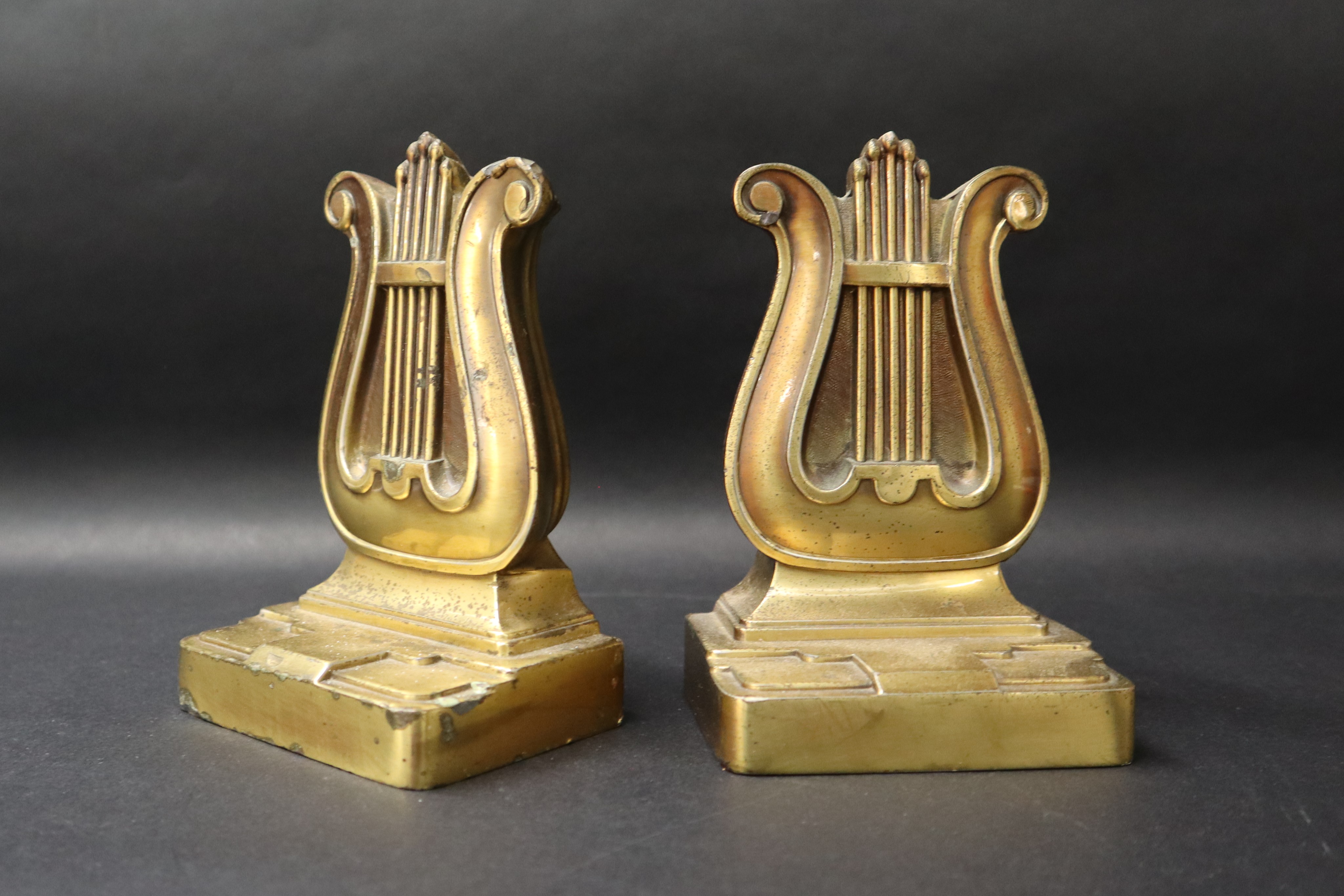 A pair of bronze book ends in the form of lyres on a rectangular base, moulded 56B PMC,