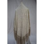 A cream silk embroidered piano shawl, decorated with figures in traditional dress,