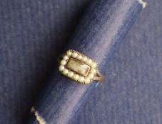 A 19th century yellow metal mourning ring set with a rectangular panel surrounded by half section