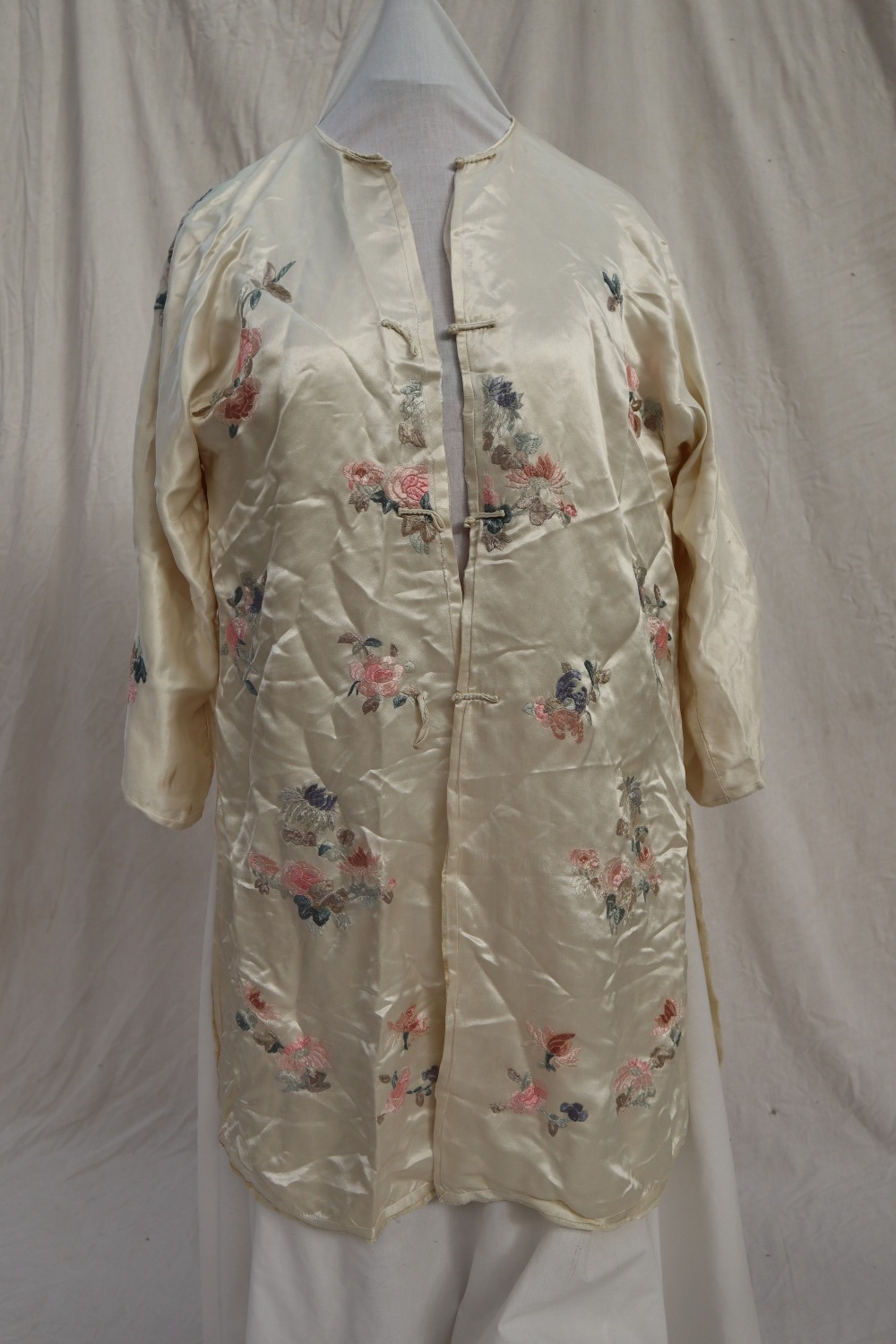 A Japanese silk kimono, the cream ground embroidered with roses and chrysanthemums,