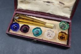 A 19th century cased set of six intaglio coloured-glass seals, with a faceted amber glass handle,