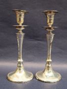 A pair of George V silver candlesticks, with a flared sconce and tapering stem on a spreading foot,
