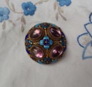A silver gilt wirework brooch set with four cabochon amethysts and enamel decoration of flowers and