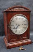 A late 19th / early 20th century oak bracket clock, with a domed top and pedestal base,