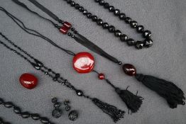 A cherry amber / bakelite necklace on black silk ribbon, together with another similar necklace,