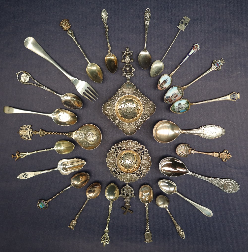 Two continental white metal sifting spoons with figural tops and leaf scrolls,
