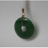 A green jade pendant of circular ring form, 4cm diameter on a yellow metal mount,