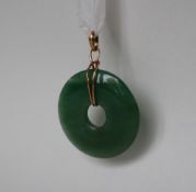 A green jade pendant of circular ring form, 4cm diameter on a yellow metal mount,