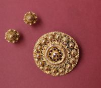 A Victorian yellow metal brooch of circular form with beaded decoration,