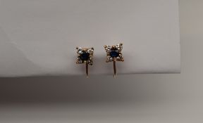 A pair of sapphire and diamond cluster earrings set with a central round faceted sapphire