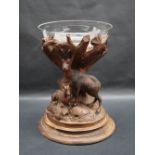 A Swiss carved table centrepiece with a glass bowl raised on a carved tree stump decorated with