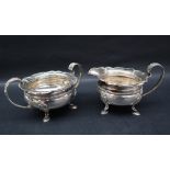 A George V silver cream jug and matching twin handled sugar basin, with a shaped leaf cast edge,