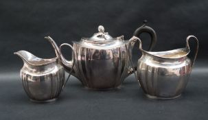 A George V silver three piece tea set, comprising a teapot with acorn finial and shaped oval body,