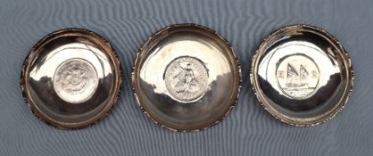 Chinese silver - A set of three Waikee sterling silver pin trays each set with a coin to the base,