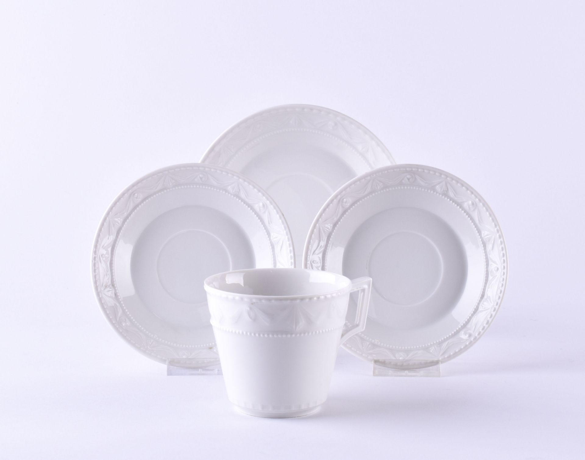 4 pieces, white porcelain, 1 coffee cup ht: 7 cm, unmarked, 2 saucers Ø 12,5 cm, each with 1 grindi