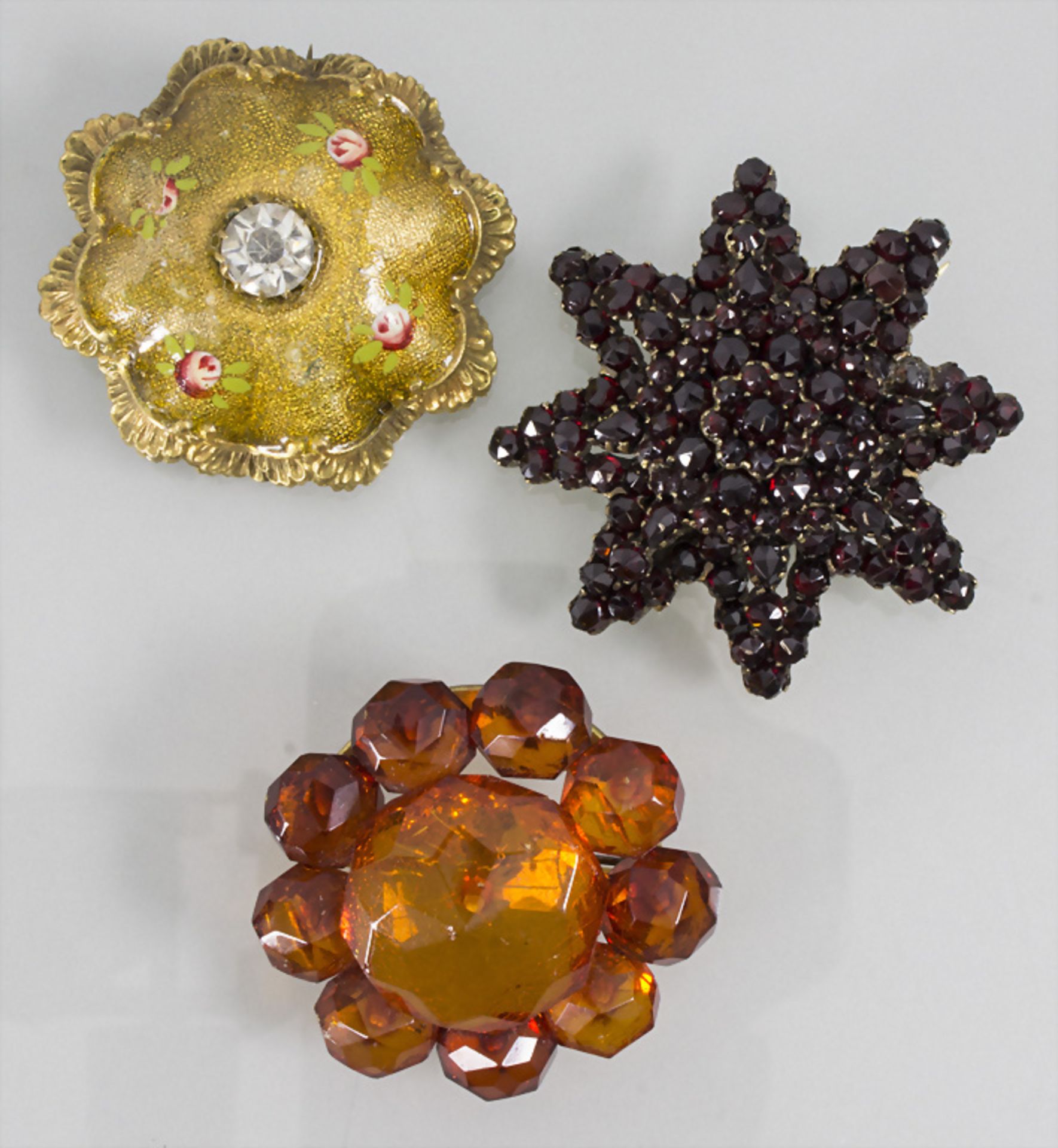 Konvolut drei Broschen / 3 brooches with garnet, amber and gold plated metal