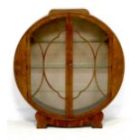 An Art Deco walnut veneered display cabinet, of circular outline, twin glazed doors, three glass