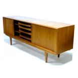 A retro teak sideboard, circa 1970, of wide low form, twin tambour sliding doors opening to reveal a
