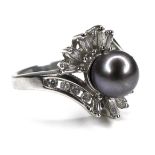 A 14K white gold dress ring, set with a 7mm black pearl surrounded by a spray of baguette and
