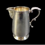 An Irish silver milk jug, of tapering cylindrical form, with foliate thumb rest and double C