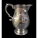 A George V silver milk jug, of baluster form, with double C scroll handle, repousse foliate