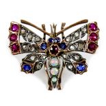 An unmarked gold brooch, formed as a butterfly, early 20th century, its wings set with white, red
