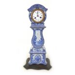 A late 19th century Blue and White Dutch Delft clock, with French barrel movement, on wooden base,