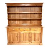 A modern pine dresser, with plate rack over three drawers and three cupboards with turned knobs, 175