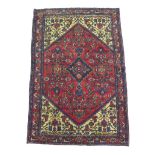 A Hamadan rug, on red ground, densely decorated field with floral and foliate detail, blue diamond