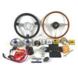 A collection of car parts and automobilia, including a wooden-rimmed Triumph steeling wheel, a
