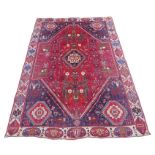A mid 20th century Persian rug, on red ground, with central diamond shaped medallion, decorated with
