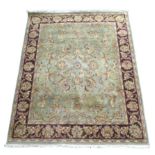 A large Chobi rug, its pale green ground decorated with a central rosette surrounded by floral