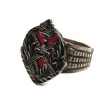 A white metal ring, with carved and pierced crest and red coral backing, 21mm wide, size O/P, 5.9g.