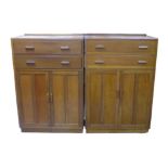 A pair of utility oak veneered chests, each with drawers over a cupboard, each 84 by 49 by 125cm