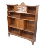 An Arts and Crafts bookcase, with pierecd decoration to its surmount, a cupboard to its middle,