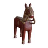 A 20th century large carved wooden horse, of naive design, painted red with gilt highlights.