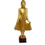 A modern gilt carved wooden sculpture of a Burmese Mandalay Buddha, in standing position with arms