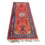 A Persian runner with red ground and blue border, 236 by 90cm.